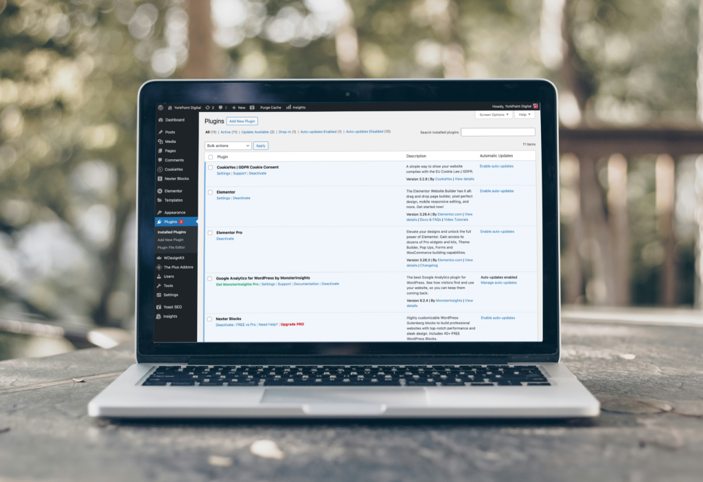 Laptop displaying the WordPress plugins dashboard, showcasing tools essential for website maintenance, updates, and security.